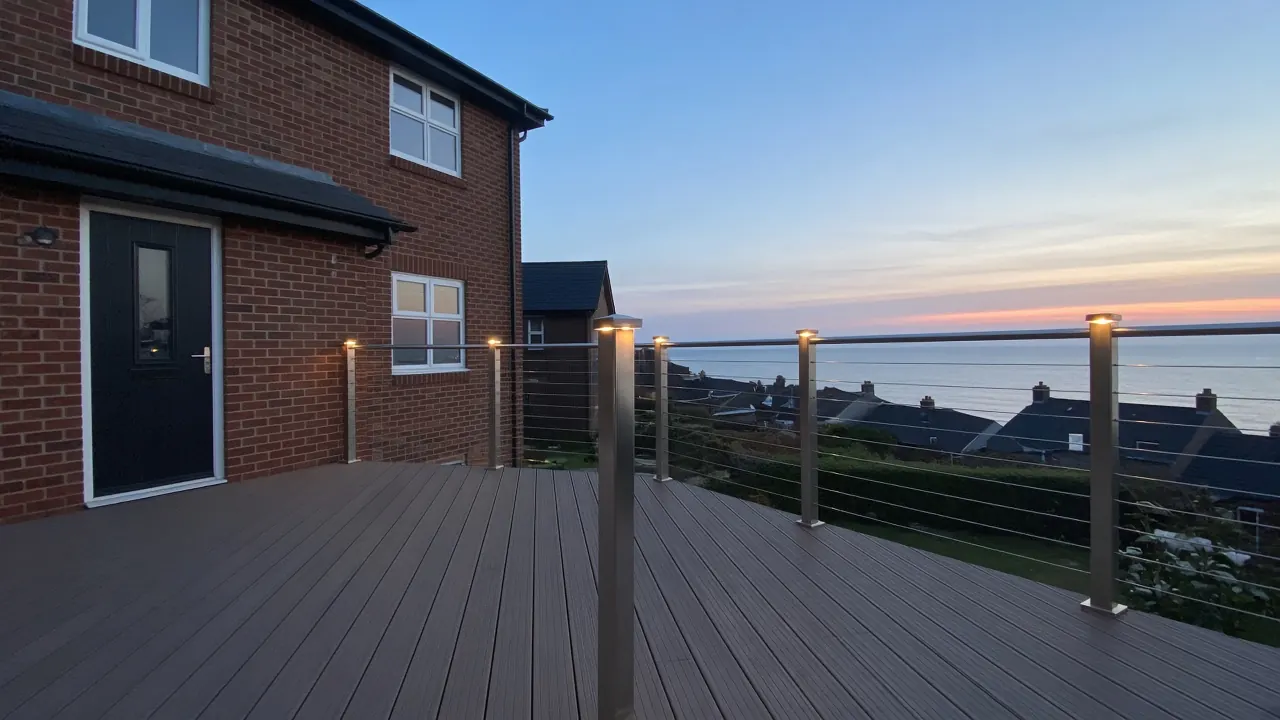 Example image: stainless-steel wire balustrade on a deck at dusk with post lights